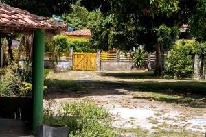 a fence with a yellow gate in front of a yard at Berlinque Pet Friendly - Muito espaço perto do mar in Vera Cruz de Itaparica