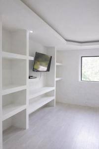 a white room with white shelves and a tv at Refugio Rio Santo in Las Alfombras