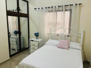 a bedroom with a white bed and a mirror at Mi casita en Jaraba in Jarabacoa