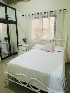 a bedroom with a white bed and a mirror at Mi casita en Jaraba in Jarabacoa