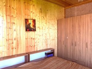 a bedroom with wooden walls with a bed and a picture at BibO in Martvili