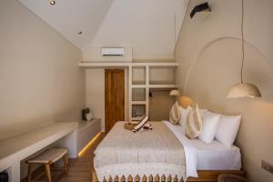 a bedroom with a bed and a desk in a room at Bebas Suites - Uluwatu, Bali in Uluwatu
