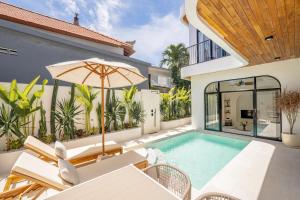an outdoor swimming pool with an umbrella and a house at Villa Arco Pererenan in Canggu +29 photos