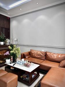 a living room with a brown leather couch and a table at HS Dobry Hotel Ha Long in Ha Long