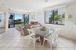 a living room with a glass table and chairs at Kings Row Apartments in Caloundra