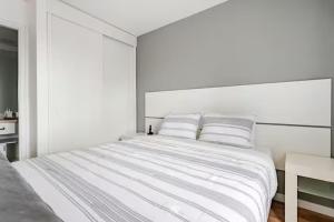 a white bedroom with a large white bed with two pillows at Flat Hotel Vila Olímpia in São Paulo