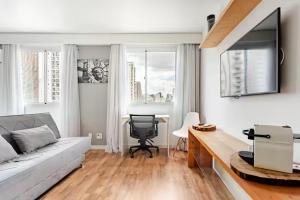 a living room with a bed and a desk with a chair at Flat Hotel Vila Olímpia in São Paulo