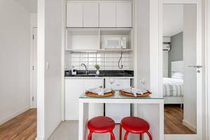 a kitchen with two red stools and a table with food at Flat Hotel Vila Olímpia in São Paulo