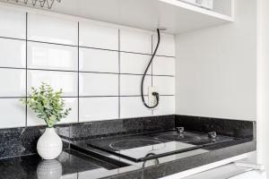 a kitchen with a sink and a vase with a plant at Flat Hotel Vila Olímpia in São Paulo +15 photos