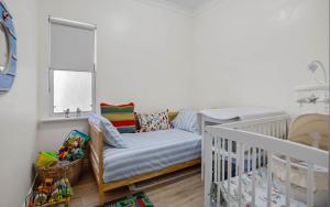 a baby room with a crib and a chair at No 11 The Smugglers Inn in Victor Harbor +7 photos