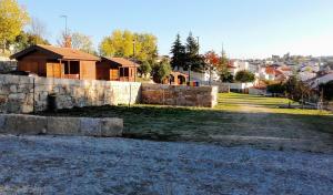 a house with a stone wall next to a yard at Douro Camping in Miranda do Douro