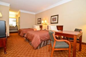 Habitación de hotel con 2 camas, escritorio y TV. en Peach State Inn & Suites, en Hawkinsville