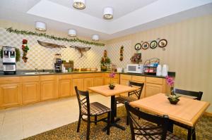una cocina con armarios de madera y 2 mesas en Peach State Inn & Suites, en Hawkinsville