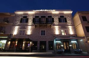 un grand bâtiment en briques avec des lumières allumées la nuit dans l'établissement Hotel Aktaion Syros, à Ermoúpoli