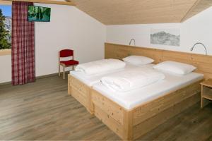 1 dormitorio con cama de madera y silla roja en Bischofalp, en Elm