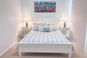 a white bedroom with a large white bed with two lamps at St Helens in Edithburgh