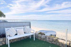 a white bench sitting on the side of a beach at St Helens in Edithburgh