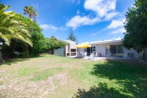a backyard with a house and a yellow umbrella at 32 Main Road in Struisbaai