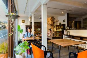 a woman sitting at a table in a restaurant at Guest House Kura in Suzaka