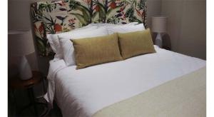 een wit bed met witte kussens en een hoofdbord met bloemenmotief bij 418 Zimbali Suites in Ballito +15 foto's