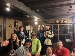 a group of people posing for a picture in a room at Guest House Kura in Suzaka