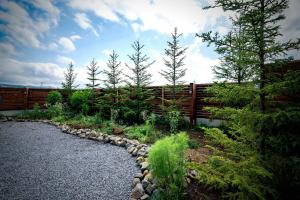 a garden with a fence and trees and rocks at ZABOCON Yoichi Villa in Yoichi