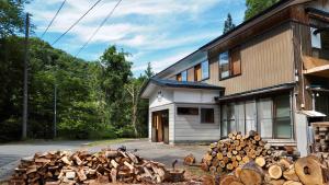 a pile of wood in front of a house at 静かな森の古民家ステイ Tunagiつなぎ in Nishiwaga