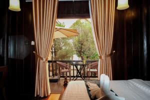 a bedroom with a bed and a balcony with a table at Bualuang Hotel in Luang Prabang