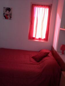 1 cama roja en un dormitorio con ventana roja en Hospedaria do Seixo, en Oporto