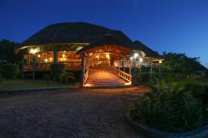 a building with stairs and a thatched roof at night at Crater Safari Lodge in Kibale Forest National Park
