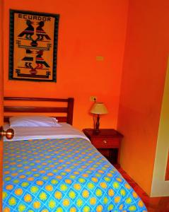 a bedroom with a bed with an orange wall at Hostal Timara in Baños