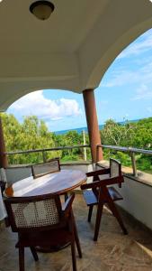 a table and chairs on a balcony with a view at Hewani a bright & airy 1 BR apartment with an ocean view & pool in Kilifi