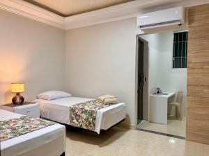 a hotel room with two beds and a bathroom at Julietta House Hotel in Manaus