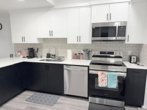 a kitchen with white cabinets and black appliances at Modern Comfort in Calgary