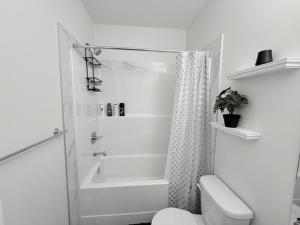 a white bathroom with a shower and a toilet at Modern Comfort in Calgary
