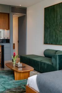 a living room with a green couch and a table at Ecoverse Resort & Residence by OXO - Nyanyi Beach, Bali in Cemagi