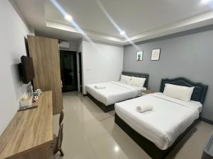 a hotel room with two beds and a television at อยู่สบายเพลส in Chonnabot