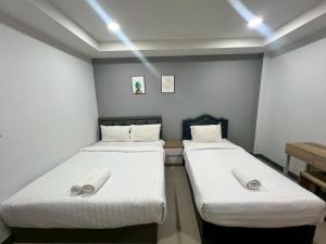 two beds in a small room with white sheets at อยู่สบายเพลส in Chonnabot