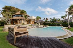 a pool in front of a house with a chair at La Joya Balangan Resort in Jimbaran