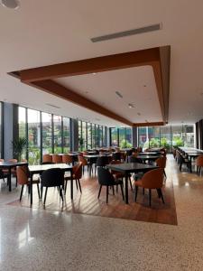 a dining room with tables and chairs and windows at Roxy Hotel & Apartment Lawas in Lawas