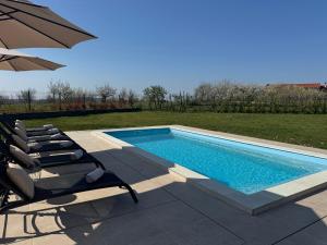 a swimming pool with two chairs and an umbrella at Capo House in Gračišče