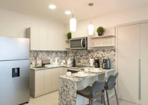 a kitchen with a counter with chairs and a refrigerator at Deluxe Loft Apt with City View in Panama City