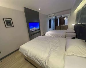 a bedroom with two beds and a flat screen tv at May Three Farm in Puerto Galera