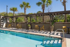 a swimming pool with chairs and tables and palm trees at Home2 Suites By Hilton Jacksonville Airport in Jacksonville
