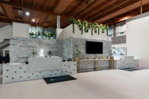 a lobby with a tv on a stone wall at Wyndham DFW Airport in Irving