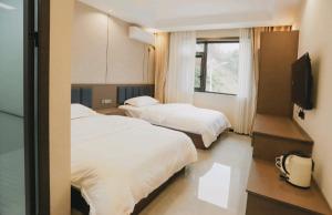 a hotel room with two beds and a flat screen tv at 福居乐 in Caodian