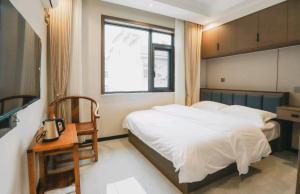 a bedroom with a bed and a table and a window at 福居乐 in Caodian