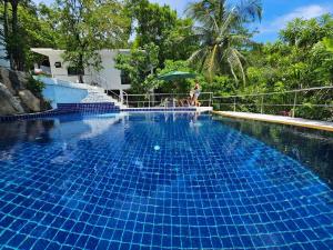 a woman sitting on a fence next to a swimming pool at v27 Sunset Horizon Villa Seaview in Haad Yao