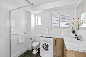 a white bathroom with a washing machine and a sink at Ocean Spray 5 in Coffs Harbour +10 photos