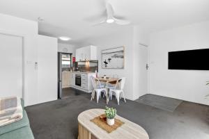 a living room with a table and a kitchen at Ocean Spray 5 in Coffs Harbour